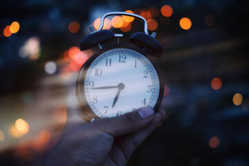 mão segurando relógio analógico