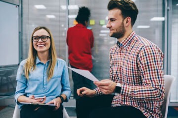 Homem e mulher em ambiente corporativo falando sobre a importância da folha de pagamento